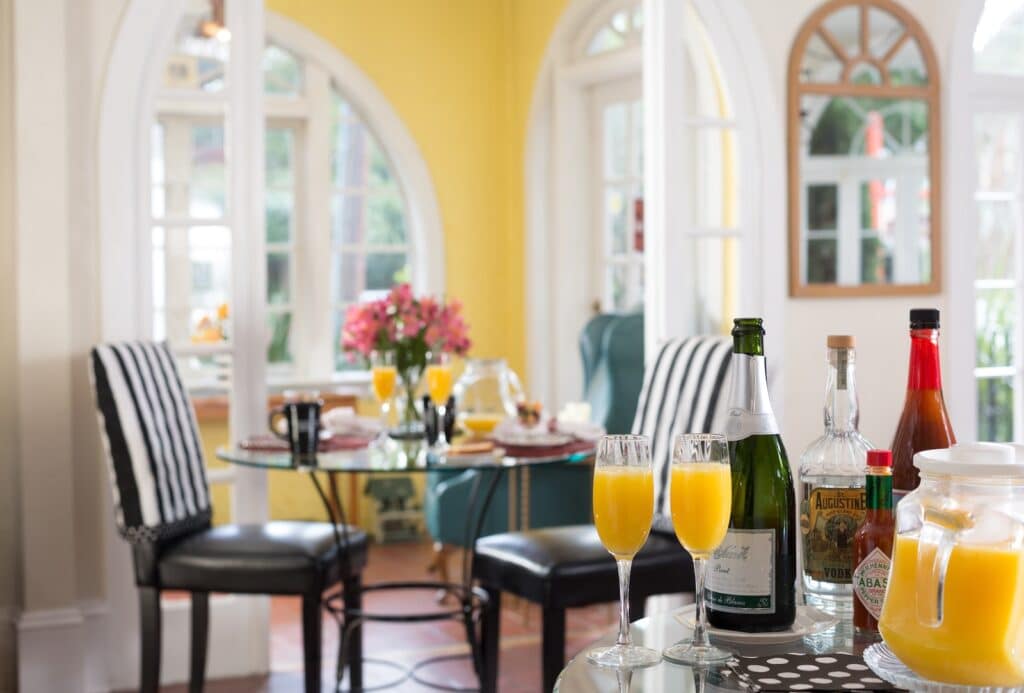 At our St. Augustine bed and breakfast, guests wake up to breakfast in a happy yellow dining room, comfy chairs by a set table, and mimosas.