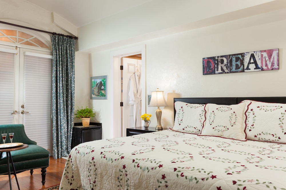 A bedroom with a queen bed, a green armchair, a nightstand, and a wall sign that reads "DREAM."