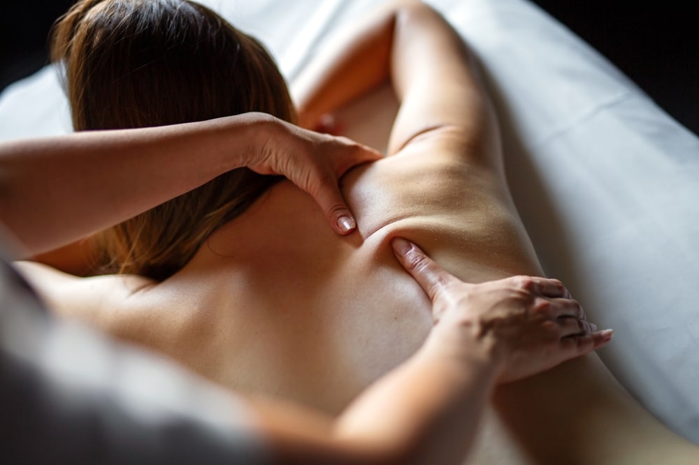 A person receives a deep tissue back massage while lying face down on a massage table.