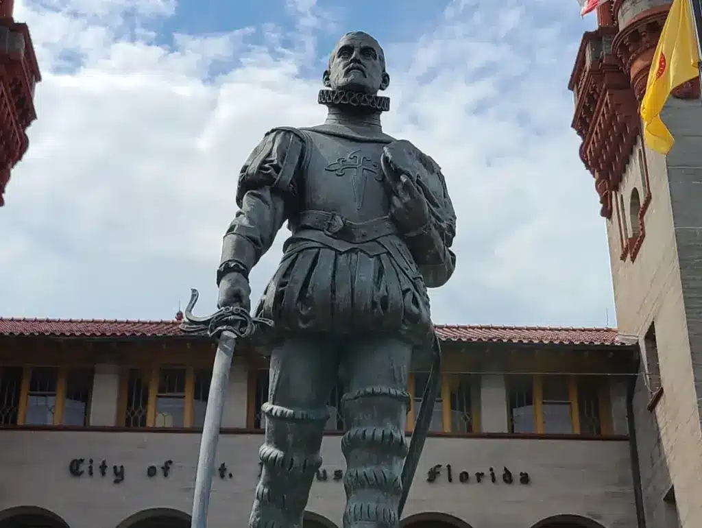 A bronze statue of a conquistador stands in front of the St. Augustine City Hall building in Florida.